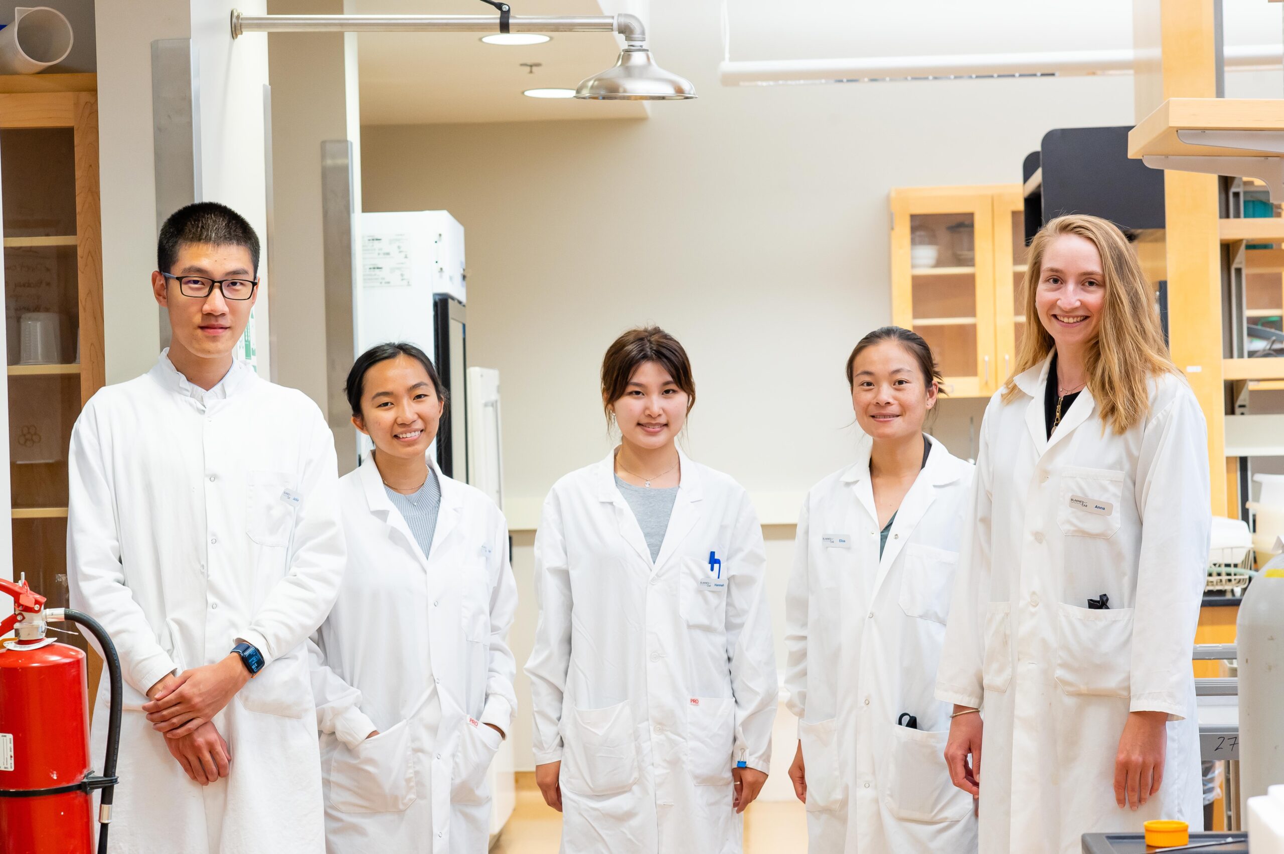 a group of scientists in white lab coats stand in a lab