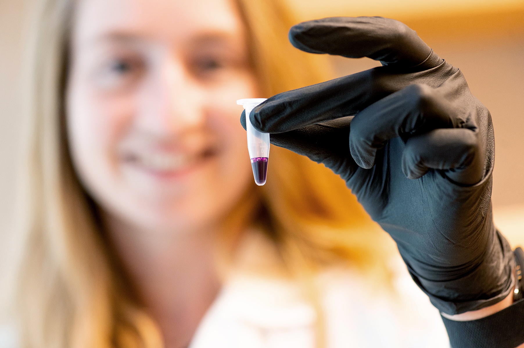 woman scientist holding up vial in lab