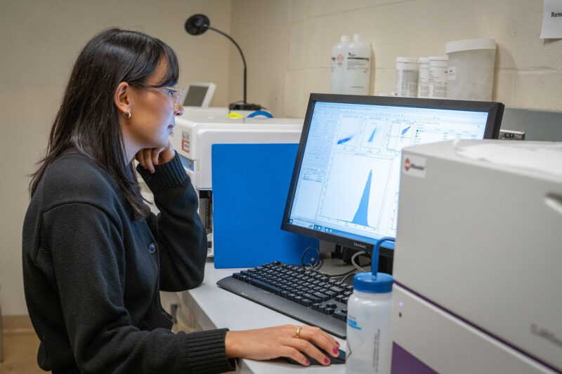 Heather Baker, sitting in front of a computer in the lab, looking at results presented on screen.