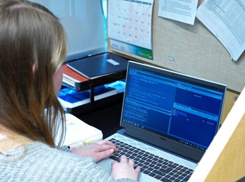 Marie Johns, seated at her work station, opening a working file in the R software.