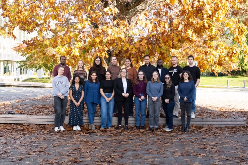 Pictured in front of a large tree with fall-coloured orange leaves is a large group of 18 researchers from the Leslie lab.
