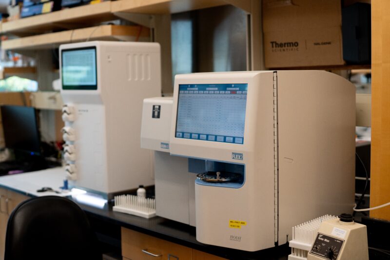 Pictured, sitting on a lab bench in the Piret lab, is the FLEX2 instrument. The instrument has a large digital display screen and an opening in the front to insert samples. The machine can analyze multiple cell culture parameters at once to characterize cell environments.